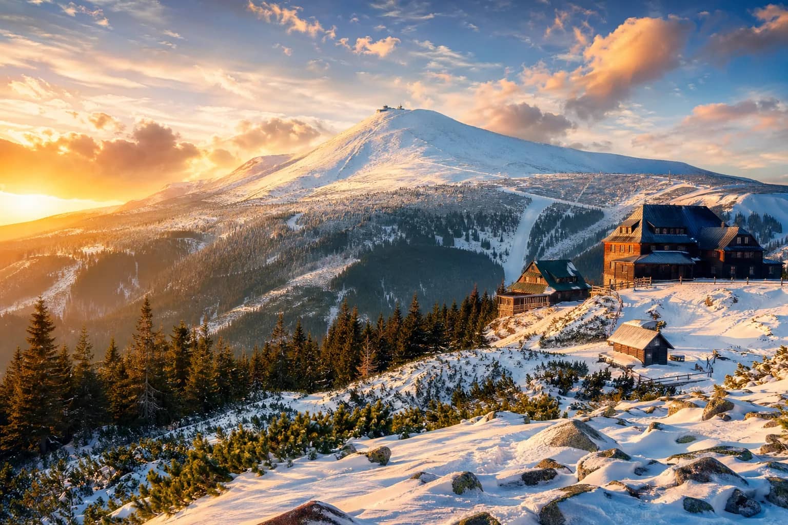 Krkonoše – panoramatický pohled na hřebeny, Sněžku, zasněžené svahy a horskou chatu v národním parku